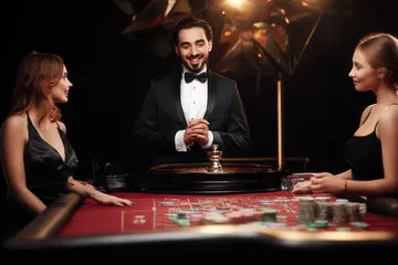 KKFBB Live Casino — Join thrilling real-dealer tables A professional dealer in a tuxedo greeting players at the roulette table, symbolizing the authentic live casino feel at KKFBB.